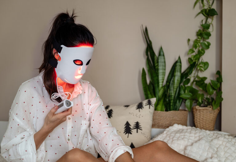 A woman is using LED red light face mask treatment