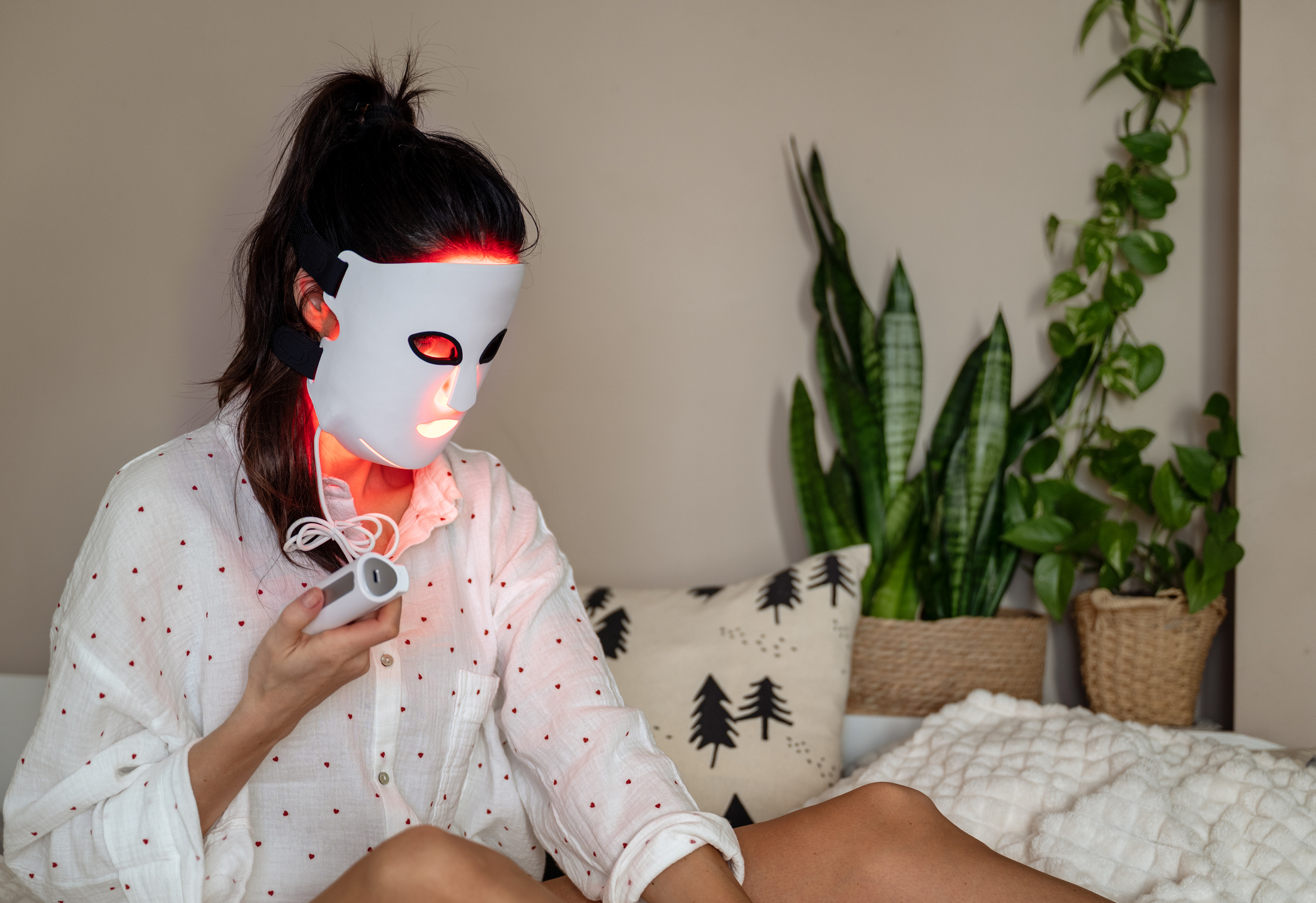 A woman is using LED red light face mask treatment
